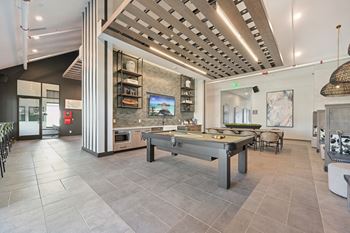 A modern kitchen with a pool table in the middle.